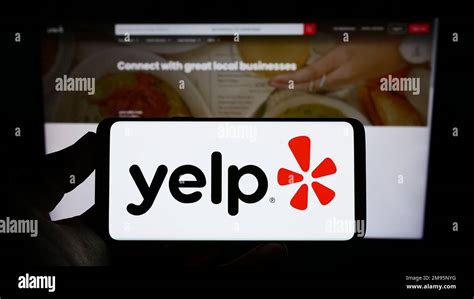 Person Holding Smartphone With Logo Of Us Review Platform Company Yelp