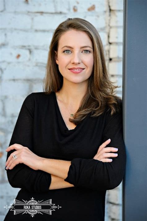 A Woman Standing With Her Arms Crossed In Front Of A Brick Wall