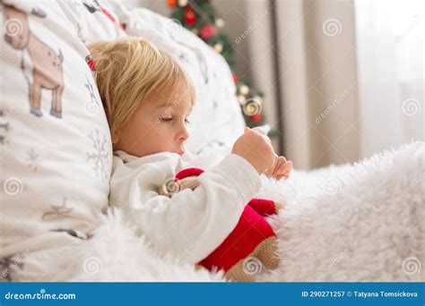 Belle Blonde Enfant Enfant Malade Garçon Avec De La Fièvre Couché Sur Le Lit De Noël Image stock