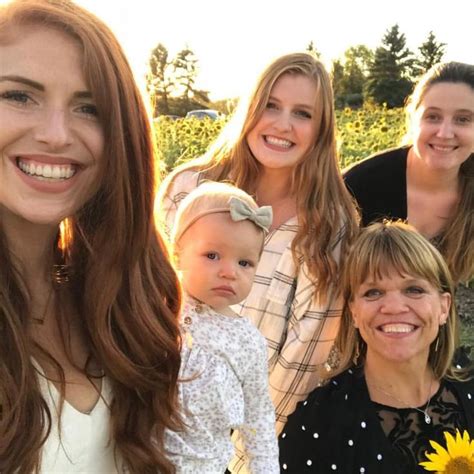 A Group Of Women Standing Next To Each Other In Front Of A Sunflower Field