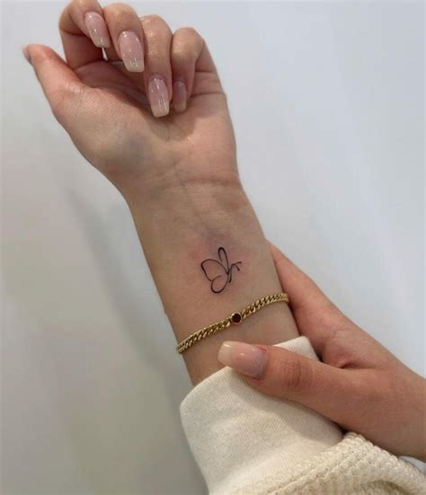 A Woman S Wrist With A Small Butterfly Tattoo On The Left Side Of Her Arm