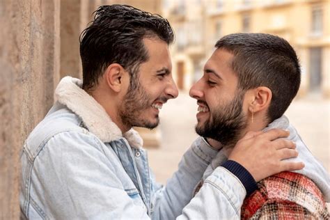 Cerca de una pareja gay joven que se ríe abrazándose y mirándose Foto Premium