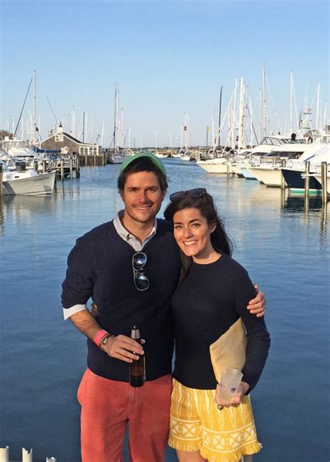 A Man And Woman Standing Next To Each Other In Front Of The Water With