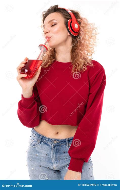 Une Jeune Fille Blonde Aux Casques Boit Du Jus D Un Verre Transparent Sur Fond Blanc Image Stock