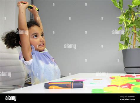 4 Year Old Latina Girl With Brunette Curly Hair Draws As Therapy With The School Psychologist