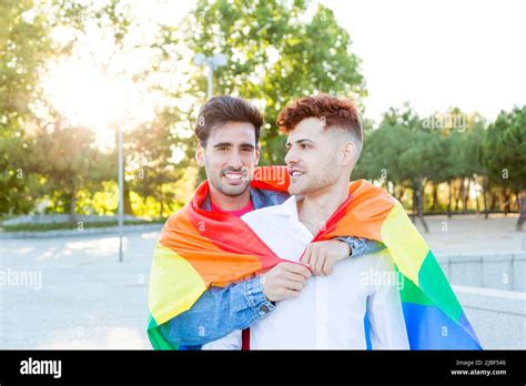 Jeune couple gay avec un drapeau de fierté LGBT tout en embrassant à l extérieur LGBT relation