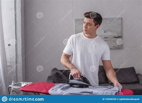 Camisa Que Plancha Del Hombre Hermoso En El Tablero Que Plancha En Sala