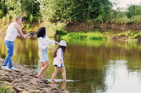 Familia feliz con caña de pescar en el río de verano Foto Premium