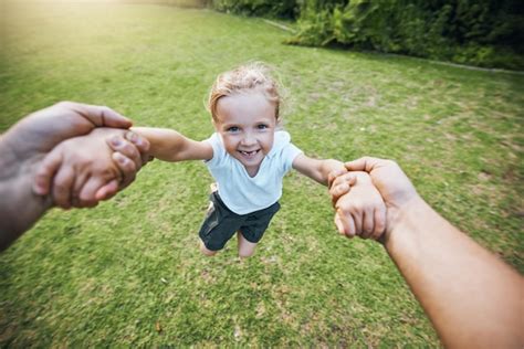 Sonrisa de parque de manos y niña balanceándose con el apoyo de la