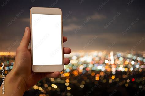 Hand holding a mobile phone with blank display, unsharp city lights in ...