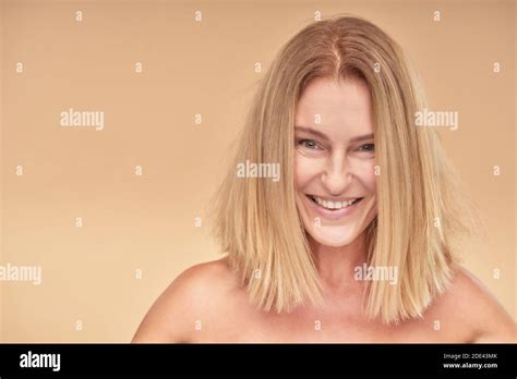 Portrait Of Attractive Mature Woman Smiling At Camera While Posing Over Beige Background Stock