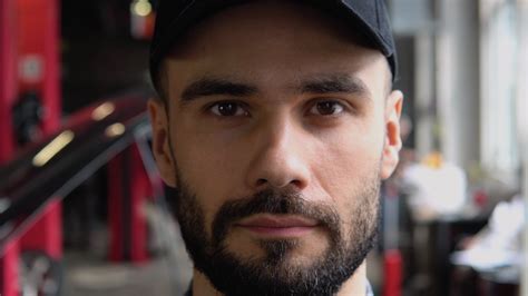 Portrait of a mechanic standing near broken car with open hood in a car