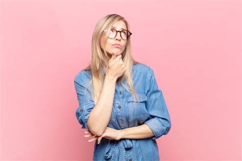 Jeune Jolie Femme Blonde Pensant Se Sentant Dubitative Et Confuse Avec Différentes Options Se