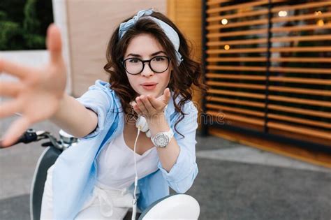 Pleased Brunette Girl Wearing Trendy Accessory Sending Air Kiss While Posing Outdoor Portrait