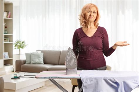 Bored Mature Woman Holding An Iron In A Living Room Stock Image Image