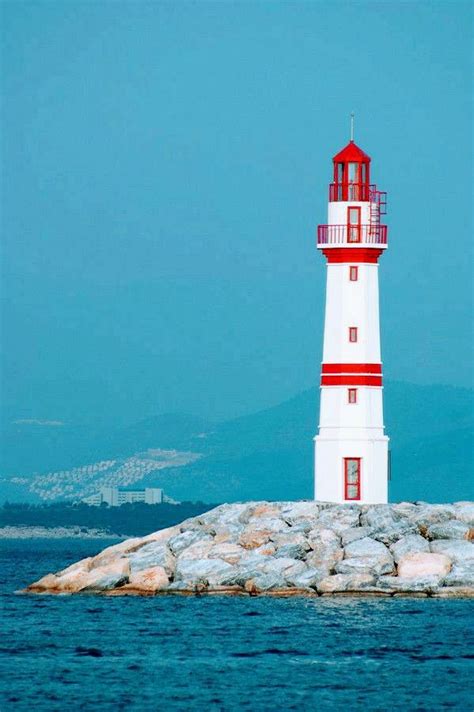 Red and White Lighthouse on Rock Formation in the Ocean