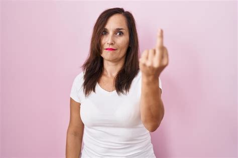Free Photo Middle Age Brunette Woman Standing Over Pink Background Showing Middle Finger