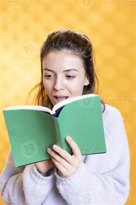 Woman gasping while reading intriguing book, feeling surprised