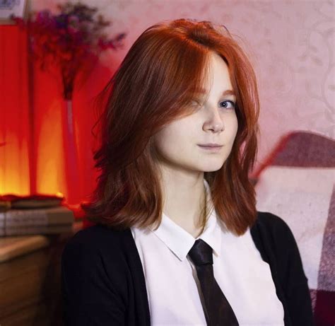 A Woman With Red Hair Wearing A White Shirt And Black Tie Posing For