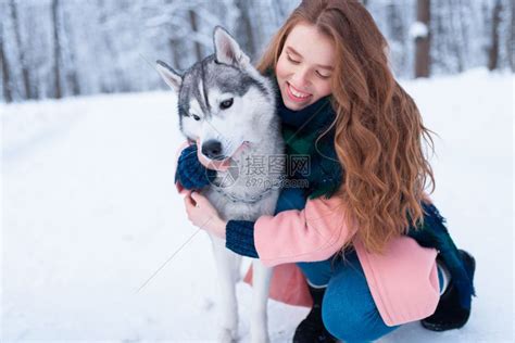 下雪的冬天年轻女子带着狗狗在公园一起在户外高清图片下载 正版图片303002705 摄图网