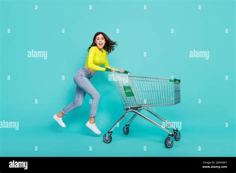 Full Body Photo Of Funny Brunette Hair Millennial Lady Jump With Trolley Wear Neon Shirt Jeans