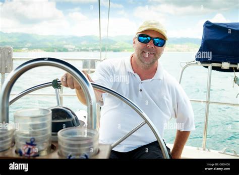 Sail Boat Captain Behind The Steering Wheel Of His Vessel Sailboat