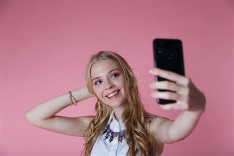 Kinky Blonde Girl Shoots Herself Smartphone Smiling On Pink Studio Background Stock Photo