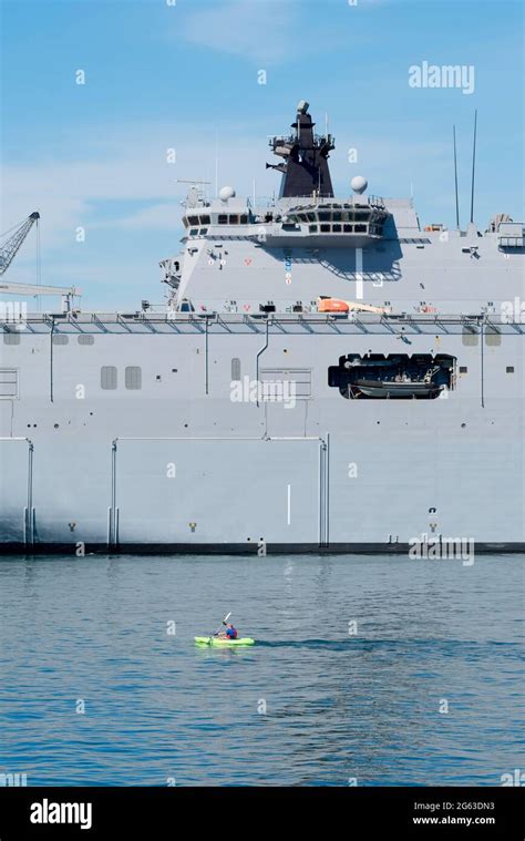 A Kayaker Paddles Beside The Royal Australian Navy Landing Helicopter Dock Ship Hmas Canberra