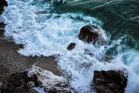 Close Up Shot Of Foamy Sea Waves Covering A Rocky Coastline Stock Photo