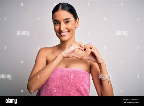 Jeune femme brunette belle portant une serviette après la douche sur un arrière plan blanc isolé