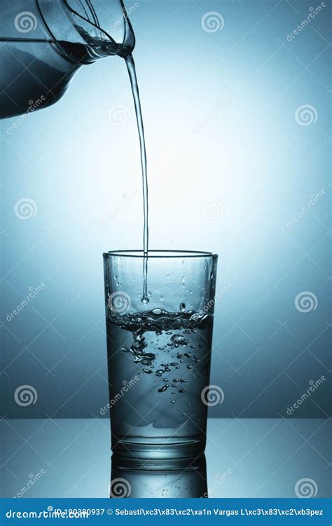 Pouring Water From A Pitcher Into A Glass Bluish Light Stock Image