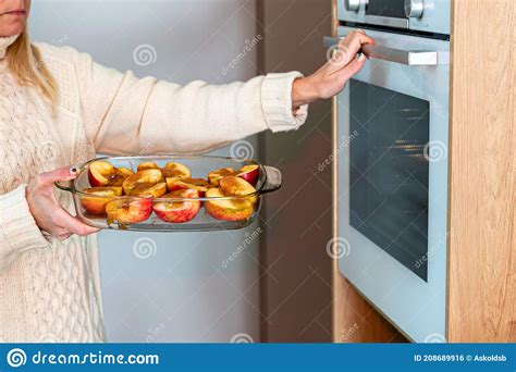 Woman Puts Glass Containers With Sliced Stuffed Apples In The Oven