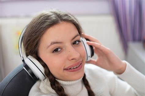 Premium Photo A Smiling Brunette In Pigtails Listens To Music On Wireless Headphones