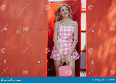 Smiling Blonde Girl Look Like A Barbie Doll In Pink Mini Dress With Pink Handbag Standing Near