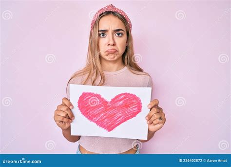 Jeune Belle Femme Blonde Tenant Le Coeur Dessiner Déprimé Et S inquiéter De Détresse Pleurer En