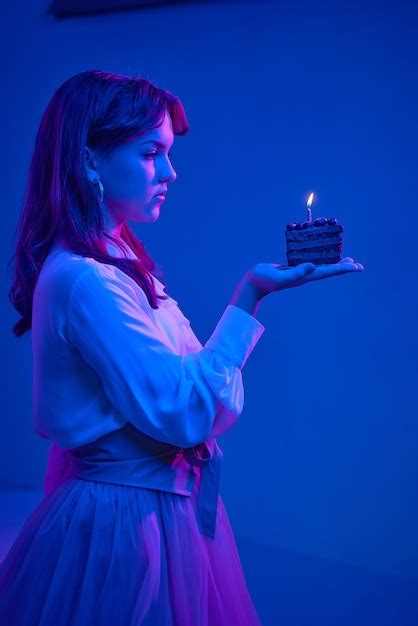 매력적인 소녀는 생일 케이크에 촛불을 끄다 생일 소녀는 우아하게 옷을 입고 그녀는 만든다 프리미엄 사진