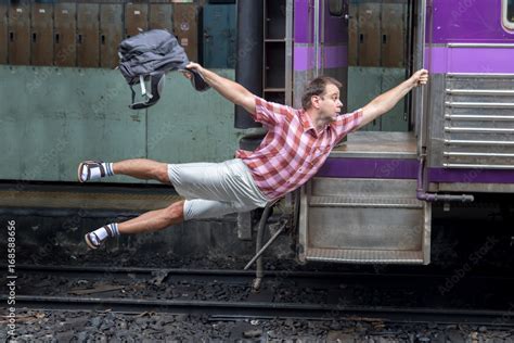 Foto De Man With Backpack Flies Behind A Moving Train Tourist Holding A Moving Train From A