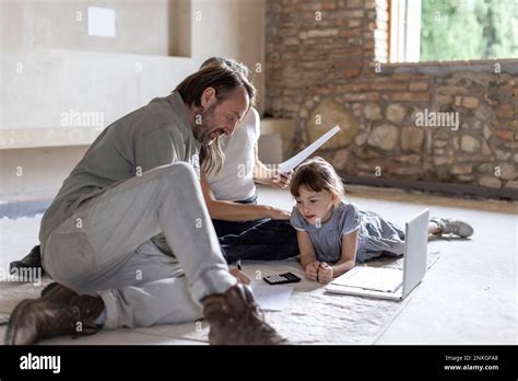 Mature Man And Woman Reading Documents With Daughter Lying On Rug At Home Stock Photo Alamy