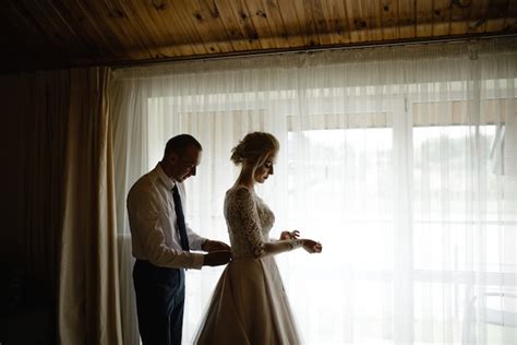 Wunderschöne blonde Braut in einem weißen Luxuskleid das sich für Hochzeit fertig macht