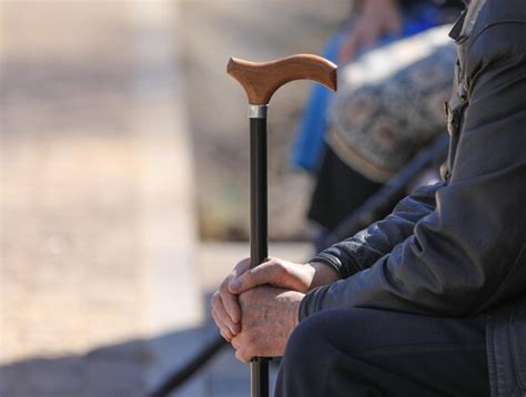 Premium Photo A Man Is Sitting With His Hands On A Cane