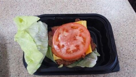 a sandwich with lettuce, tomato and cheese in a black container on a table