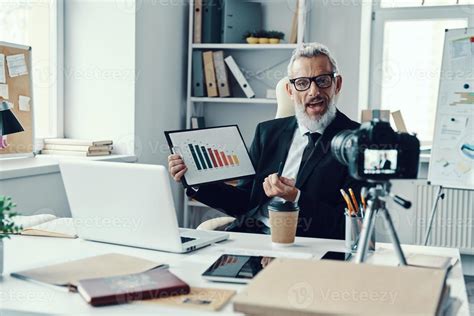 Confident Mature Man In Elegant Suit Showing Chart And Sharing Business Experience While Making