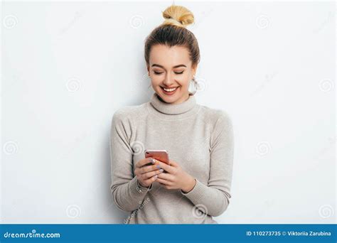 Happy Cheerful Glad Woman With Hair Bun Nude Makeup Wearing In Sweater Standing Indoors With Her