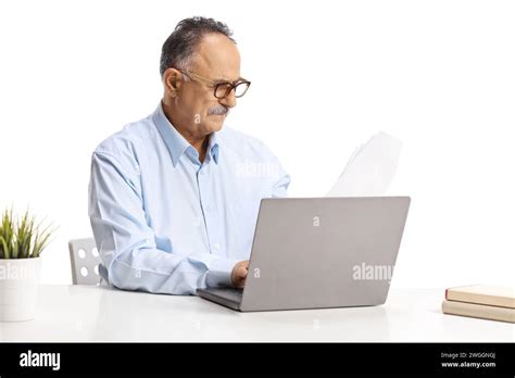 Mature Man Sitting At A Desk And Working On A Laptop Computer Isolated On White Background Stock