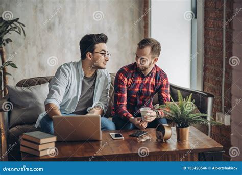 European Gay Male Couple Spend Time Together Drinking Coffee And Watching Laptop Stock Photo
