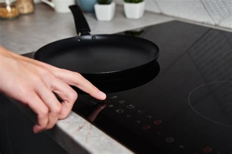 Premium Photo Woman Hand Turns On Modern Induction Stove In The Kitchen