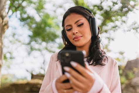 Hermosa chica latina usando su teléfono móvil en el parque Foto Premium