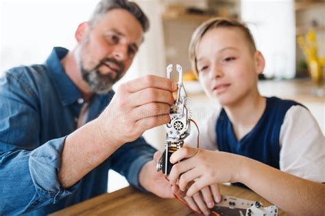 Mature Father With Small Son Sitting At Table Indoors Working On School Project Stock Image