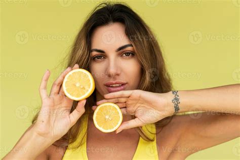 Beautiful Woman Posing Over Green Background Holding Fresh Lemons