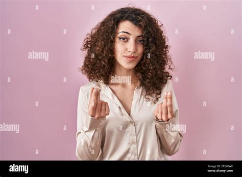 Hispanic Woman With Curly Hair Standing Over Pink Background Doing